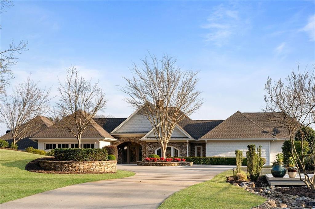 Step into a realm of unparalleled luxury nestled along the pristine shores of Lake Lanier. This meticulously curated estate is more than just a residence; it's a lifestyle sanctuary where elegance and tranquility intertwine, inviting you to embrace the essence of lakeside living at its finest. Prepare to be captivated from the moment you arrive, as the estate's breathtaking setting unfolds before you. Set on 1.15 acres of lush waterfront land, it commands an enviable position, offering uninterrupted panoramic views of Lake Lanier's tranquil expanse. Every inch of this meticulously designed residence has been crafted to celebrate the natural beauty of its surroundings, creating an unparalleled living experience that seamlessly blends luxury with nature. Enter a world where every moment is an opportunity to savor the art of living. From the grand entrance, you're greeted with sweeping vistas that capture the ever-changing beauty of the lake, from the soft hues of dawn to the mesmerizing spectacle of twilight. Each moment becomes a celebration of nature's grandeur, inviting you to immerse yourself fully in the magic of lakeside living. Venture outdoors, and you'll discover an oasis designed to elevate your leisure pursuits to new heights. Challenge friends to a game on the expansive tennis court, freshly lined for pickle ball or tennis enthusiasts. Take a refreshing dip in the heated infinity edge pool, its seamless design merging effortlessly with the vast expanse of Lake Lanier. And when it's time to unwind, retreat to the sun-drenched patio, where lush greenery and the soothing sounds of nature create the perfect backdrop for relaxation. With nearly 330 feet of shoreline, this estate offers an unparalleled sense of privacy and tranquility, allowing you to escape the hustle and bustle of everyday life. Indulge in water sports, soak up the sun's warmth, or simply revel in the serenity of nature's embrace. Discover the island just a stone's throw away, reachable by either the sandbar or a quick swim. The two islands opposite the house form a distinctive barrier, lending an intimate cove ambiance to the expansive water vistas, ideal for leisurely swims and basking in the sun on the two-story dock. Complete with dual jet ski docks and two slips featuring HydroHoist boat lifts, the dock is fully equipped to cater to your aquatic adventures. Inside, luxury awaits at every turn, with two fully equipped kitchens boasting top-of-the-line appliances and ample storage spaces ensuring effortless organization. Earth tones reign supreme throughout, with timber, steel, stone, and leathered granite infusing the space with warmth and character, creating an atmosphere that is both inviting and elegant. More than just a home, this estate is an embodiment of luxury, tranquility, and endless possibilities. Whether you're seeking a serene escape, a venue for unforgettable gatherings, or a place to create cherished memories, this property promises to exceed your every expectation. Embrace the essence of lakeside living and discover the unparalleled lifestyle that awaits at this exquisite estate. Immerse yourself in the grandeur of its surroundings, indulge in its luxurious amenities, and create a lifetime of memories amidst the breathtaking beauty of Lake Lanier. Schedule your private tour today.
