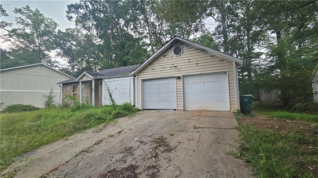 Garage featuring concrete driveway and view of scattered trees