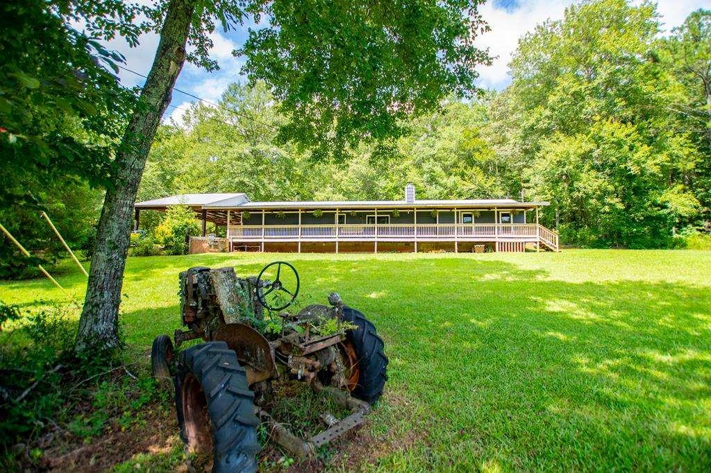 Set on 22.63 acres in beautiful Heard County, this renovated five-bedroom, three-bath ranch pairs country charm with modern comfort. The newer metal roof and freshly painted interior welcome you home to wide-open spaces, where pasture meets hardwoods and a quiet creek winds its way through the land. The heart of the property is a spacious, light-filled home with newer LVP flooring throughout and a recently updated interior. The primary suite feels like a private retreat, featuring a walk-in tiled shower and luxurious finishes. A wood-burning stove warms the entire home with ease, though propane heat and a traditional fireplace remain options for those who prefer them. Outside, a covered country deck with classic porch is an ideal place to watch sunsets and entertain family. A four-car carport, pole barn, and storage building provide abundant utility, while a handcrafted wood playhouse provide abundant fun for the kids. Cattle have thrived here, watered by the creek, but the land is versatile-ideal for horses, gardening, or simply room to roam. The property is on well water, with a county water tap already in place at the street for future convenience. Every detail has been considered to create a home that feels solid, welcoming, and ready for your family. This is more than a place to live. It's a place to breathe. A place to grow. A place to settle in and call your own.