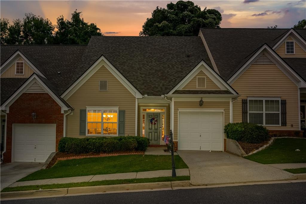 Exterior featuring a light tan siding facade with brick accents and a shingle roof