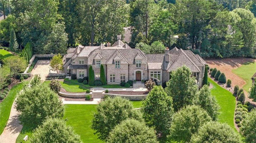 Welcome to unparalleled luxury in The Hayfield, Milton’s most prestigious gated community.
Designed by the renowned architect William T. Baker and built by Jacklett Construction, this
extraordinary custom home is a masterpiece of timeless elegance and impeccable craftsmanship. The home was designed for low maintenance with an old Savannah brick exterior and Marvin aluminum clad casement windows and doors set off by brick molding. Mature landscaping, designed by LandPlus, frames the home and creates a private oasis with stunning sunset views.

The cedar shake roof, copper gutters, limestone surround, and custom solid mahogany front door set the stage for the extraordinary details found within. Step into the foyer with French oak flooring laid in a Versailles pattern and exquisite millwork. A 22’ vaulted living room with
walnut beams and limestone fireplace, and the dining room with lacquered bar and an antique
crystal chandelier flank the foyer.

This residence offers five bedrooms each with ensuite bathrooms, and four half bathrooms. The main-level primary suite has French doors that lead directly to the rear garden and pool, creating a seamless connection to the home’s outdoor retreat. The primary bath has heated marble floors, a towel warmer, and a steam shower with integrated sound system. A main-level home office with balcony offers breathtaking views to complete the primary wing.

The heart of the home is the chef’s kitchen, a true masterpiece equipped with a LaCanche double oven gas range featuring a French simmer plate, grill, and wok accessories. It is complemented by a Sub-Zero refrigerator/freezer, additional refrigerator and freezer drawer units, and a scullery that includes a Bosch dishwasher, an icemaker, and a Miele wall oven, microwave, and warming drawer. Every detail of this space is designed for culinary excellence. Through the adjoining keeping room, step outside through the spectacular steel doors to discover a breathtaking outdoor retreat. The covered patio with vaulted ceiling, stone fireplace and built-in grill creates the perfect venue for outdoor gatherings. A heated saltwater pool and spa, complete with lighting and a tranquil fountain feature, invite you to relax and unwind. Nearby, a putting green provides an opportunity for leisure. An outdoor powder room and a well irrigation system ensure that every detail is as functional as it is beautiful.

The upstairs area is equally impressive, offering a sitting room for relaxation or entertaining
surrounded by three spacious ensuite bedrooms. These thoughtfully designed spaces cater to a range of needs and ages.

The finished basement offers a world of possibilities. Here, you’ll find luxurious millwork
adorning the kitchenette, a cozy family room perfect for movie nights with a powder bath, an
exercise and game room, a serene sitting area, an ensuite bedroom, and ample storage options.

Advanced smart home technology allows you to control the home’s systems with ease, from the zoned Trane HVAC and Honeywell security system to the Ring doorbell cameras and Crestron/Sonos whole-house music and entertainment system. Every inch of this property is crafted for luxury living. From its elegant interior spaces to its stunning outdoor amenities, this home is a rare gem in Milton’s most coveted neighborhood. It’s more than a residence; it’s a lifestyle. Don’t miss the opportunity to own this one-of-a-kind estate in The Hayfield.