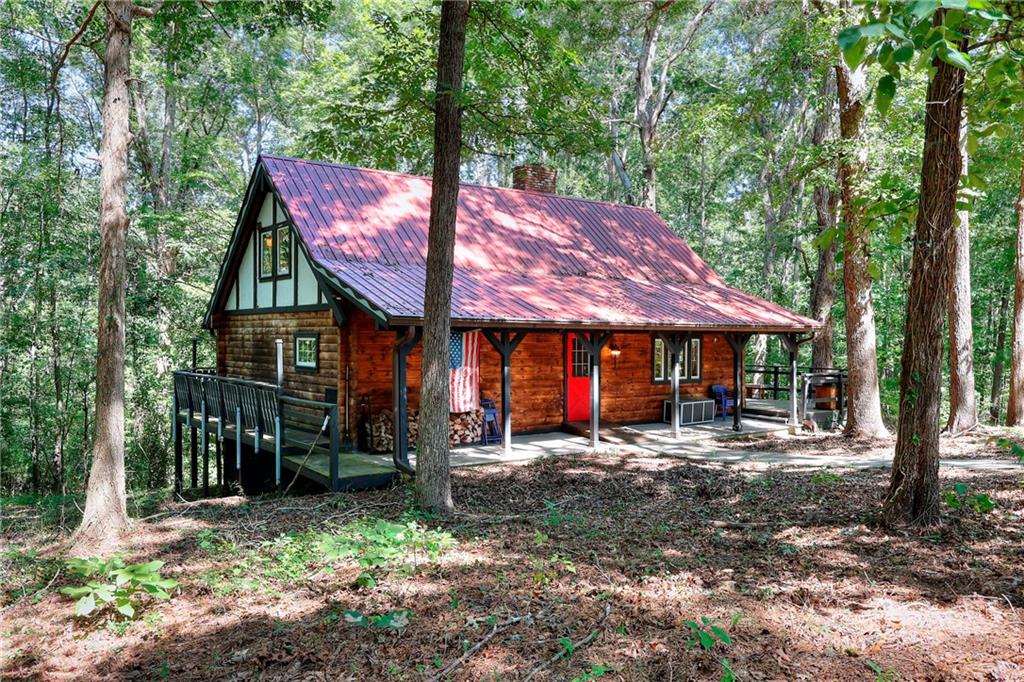 Adorable Log Cabin tucked away on 8.5 private wooded acres with Creek. Winding driveway leads you to this lovely home featuring a Covered Front Porch and expansive decking all the way around the home, great for entertaining or just enjoying the privacy in the woods. Vaulted Great Room has large Masonry fireplace, w/ built-In wood storage, Built-In Bookcase, Main floor features Vaulted Beamed Ceilings, Beautiful Log walls and lots of windows. Nice size kitchen includes Smooth Electric Cook-top, Wall Oven, Fridge, Wood Cabinets w/ Glass doors & Undercabinet Lighting. Bright Dining Area has sliding door to Back Deck. Master Suite on Main has Walk-In Closet and tub/shower combo. Additional 1/2 bath on main. Good size Laundry Rm on main with storage. Upstairs has a Bedroom w/ Vaulted Ceiling & Cedar Closet, plus extra storage under the eaves. Full Finished Basement has Workshop area, Rec Room and Bedroom with built-in Murphy Bed & Sliding doors to large Back Patio. Driveway access down to lower level. Log style Storage Building with power and covered equipment area. Home is on well water, but there is county water & natural gas available at the street. 461 ft of road frontage, property could possibly be split and build another home on it, would need to verify with county. Home being sold as-is. Fridge, Washer/Dryer Included.