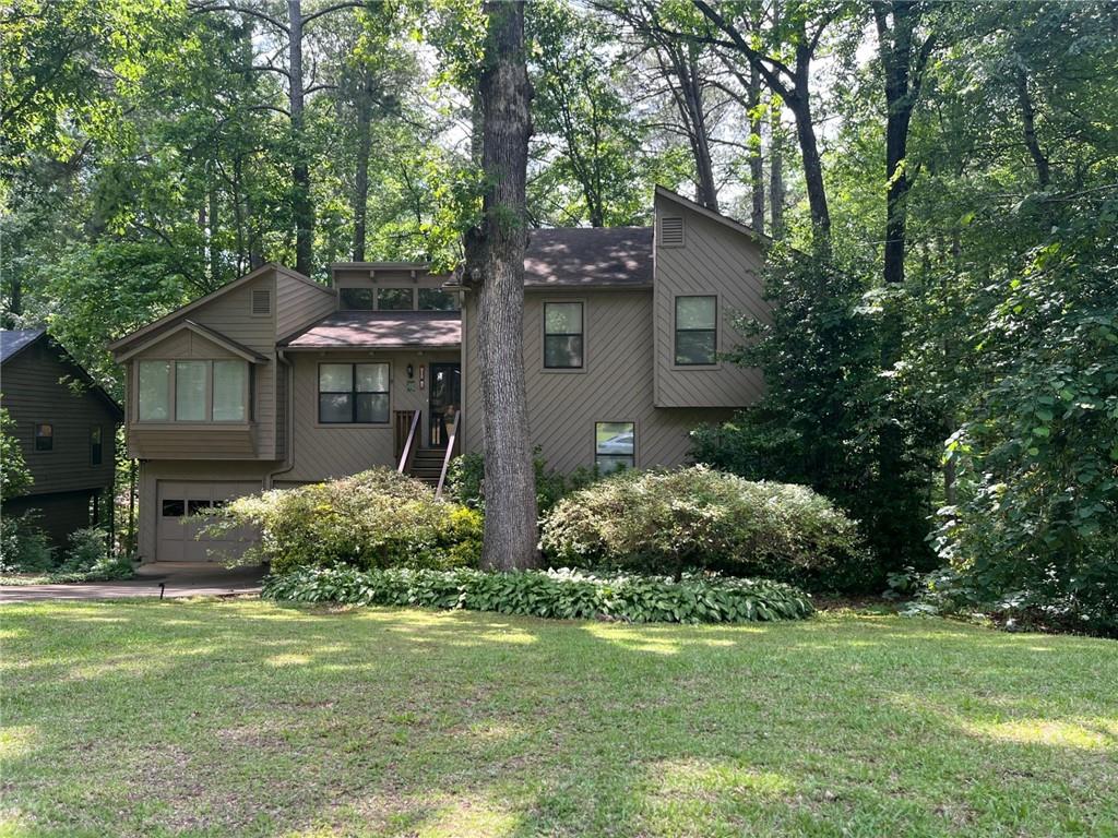 Move in ready home with quick sale possible! Enjoy wood beams adorning the cathedral ceiling in an open great room with large fireplace. The great room opens to the Dining room which has a built-in window seat. The adjacent kitchen has white cabinetry & a breakfast area. This spacious East Cobb home includes an additional 4th room, not tech classified as a bedroom due to the lack of a built-in closet, but features a sliding glass door to an outside deck and easy access to the laundry room and a potential on suite. This room is ideal for use as a guest room, playroom, or any purpose you may require. There is a workroom room/hobby room/office under air, in the laundry room. All rooms in the home are generously sized. There is a 30-year architectural roof, and the home exterior is Concrete Block base and Cedar.
This residence is impeccably maintained by owner. The two garage provides ample space for hobbies, storage, & lawn equipment. Step out onto the deck and enjoy the serene views a wooded backyard, offering a sense of seclusion. Despite its tranquil setting, the home is conveniently located just minutes from Highway 92, near downtown Woodstock, and only few miles to Highway 575. This property offers far more than a typical three-bedroom, two-bathroom layout, providing space to accommodate every family member. Situated in a peaceful friendly neighborhood with No required HOA. A voluntary annual HOA fee of $30 covers the entrance landscaping & social activities.