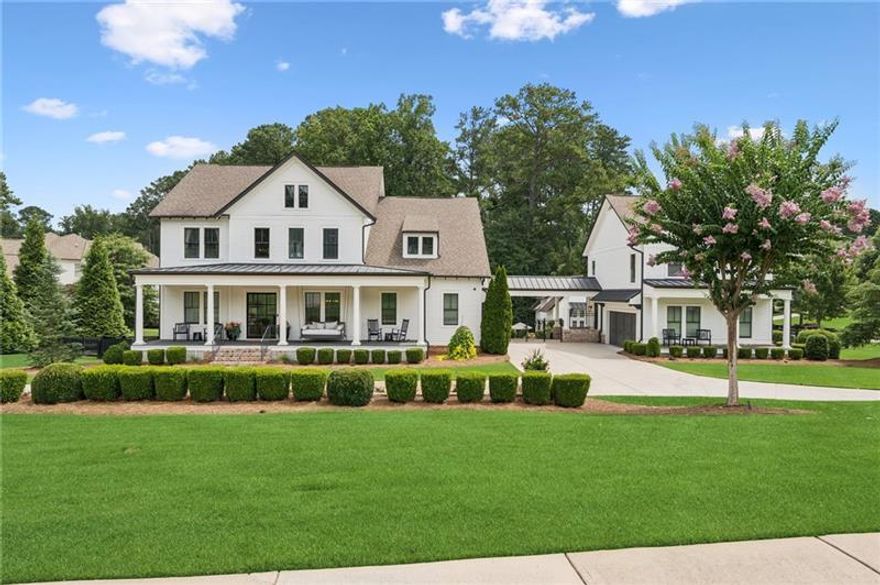 Welcome to this extraordinary former model home in The Grove, one of Milton's most coveted communities, known for its rolling landscapes, peaceful setting, and proximity to award-winning schools, including Birmingham Falls Elementary, Northwestern Middle, and Milton High. This is an incredibly rare opportunity featuring a pool, a four-car garage (including a detached two-car garage with a full living suite above), a detached pool house, and a beautifully fenced-in property. This residence effortlessly blends sophisticated design with everyday comfort, offering up to seven bedrooms, six and a half bathrooms, and countless high-end details throughout. The detached two-car carriage house includes a complete living suite with a full kitchen, washer and dryer, and a full bathroom perfect for guests, a private office, or additional living space. A wide rocking chair front porch leads to a striking custom iron front door and into a grand two-story foyer that sets the tone for the home's elegance. The open floor plan is anchored by a spacious great room with coffered ceilings, flowing seamlessly into a chef's kitchen complete with a six-burner range, pot filler, oversized island, ice maker, butler's pantry, and an expansive walk-in pantry. Just off the kitchen, a vaulted keeping room with a cozy fireplace creates a warm and inviting atmosphere, ideal for both entertaining and quiet evenings at home. The main level includes a beautifully designed mudroom with abundant built-ins, a glass and iron accent door, built-in washer and dryer, and an LG Styler steam unit an unexpected luxury that adds ease to daily living. The primary suite is a true retreat, featuring tray ceilings, a large custom walk-in closet, and a spa-like bathroom that includes a freestanding soaking tub, dual vanities, and an expansive double shower with high-end finishes throughout. Upstairs, four generously sized bedrooms are accompanied by three full bathrooms, offering comfort and privacy for family or guests. The bonus space over the family room can be used as an additional bedroom suite, as a home office or an additional family room, providing valuable flexibility for a variety of needs. The finished terrace level expands the home's livable space and offers exceptional versatility, with a private bedroom and full bathroom, a fully equipped second kitchen with a large island, wine fridge, microwave, and ice machine, as well as dedicated areas for a home gym, game room, and media room. Whether entertaining large groups or accommodating extended family, this level is designed to adapt beautifully to any lifestyle. Set on a beautifully manicured one-acre lot, the outdoor living spaces are equally impressive. The backyard features a saltwater pool and a resort-style pool house with vaulted ceilings, exposed wood beams, a fireplace, and a comfortable lounge area. A flat, expansive front yard with a circular driveway and a fully fenced backyard complete the setting, offering both space and privacy in a peaceful residential environment. Ideally located just minutes from Scottsdale Farms, The Union Restaurant, Seven Acre BarNGrill, and Downtown Crabapple with easy access to Downtown Alpharetta, Avalon, and GA 400 this home offers the perfect balance of tranquility and convenience. Timeless style, impeccable craftsmanship, and luxurious amenities come together in this one-of-a-kind Milton residence, where everyday life feels like a retreat. Welcome home.