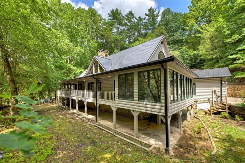Spectacular River Frontage on the CARTECAY RIVER overlooking Blackberry Falls! This 2.56-ACRE RIVERFRONT ESTATE offers the rare opportunity to own a true River Lodge on the ever popular "SHOALS",where the whitewater rapids of the Cartecay River meets exposed rock formations, creating mini-rapids and beautifulsounds of rushing water. This property is an ideal spot for relaxing by the water or enjoying kayaking and tubing over the falls. ***This is a special property indeed with no HOA, all paved roads and less than 5 miles from town.*** Inside, an open-concept design welcomes you with soaring cathedral ceilings, custom wood accents, built-in bookcases, and a gorgeous stone wood-burning fireplace. The spacious kitchen features abundant cabinetry, walk-in pantry, stainless appliances, and seamless flow to the dining area and sunroom, perfect for enjoying the views and sounds of the river. The luxurious oversized primary suite includes a steam shower, jetted tub, and private retreat space while the upper level offers two expansive guest suites, 2 half baths and a joint spa-like bathroom. (Upstairs banister handcarved and imported from Sweden.) Enjoy the outdoors from the all-NEW PARTY PORCH overlooking the falls, a new FIREPIT along the river's edge, or the wraparound covered porches. Upgrades include NEW: metal roof, exterior paint, lighting & fans, Generac whole-house generator, refrigerator, dishwasher & garage door system. There is also a stunning custom stone entry wall, koi pond, and level yard with easy river access. Additional features: 2-car garage, gated entry, paved roads, public utilities, hi-speed internet, and no HOA fees. Less than 5 miles from Downtown Ellijay, this home is privately tucked away yet close to shopping, dining, and wineries. Flood insurance not required. This home has never been a vacation rental; however, STR's are allowed.