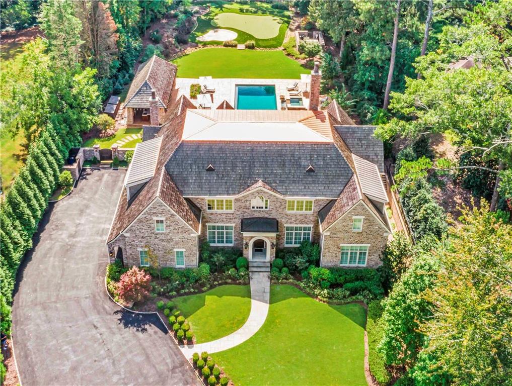 Stunning Harrison Design home, built by Crestar, is a one-of-a-kind private estate with gated entry in the heart of Buckhead. Set back from the road this exceptional property offers over an acre of flat outdoor living space. Inside you’ll find the perfect floor plan; high ceilings, tons of natural light, and luxurious finishes throughout. The huge open kitchen has a custom walnut island and is open to a coffered ceiling fireside great room. The breakfast room and great room have floor to ceiling windows overlooking the incredible pool and grounds. Vaulted lanai with fireplace and 15ft glass accordion doors to the outside. Primary suite on main with hidden access to a front office also includes a marble spa-inspired bath with slipper tub and large frameless shower with dual shower heads & custom closets. There is another main suite upstairs and second laundry room. Upstairs also includes a large loft area, perfect for an additional living space, home school or recreational space and generous bedrooms with en-suite baths. 3 car side entry garage with carriage doors. Terrace level with impressive gym, custom media room, awesome bar & billiards areas that are open to the fireside living space plus a guest/in-law suite with full bath. Elevator to all 3 floors. This home is loaded with all the bells and whistles you can imagine. The private resort-style walk out backyard has a large, salt-water, heated pool & spa, putting green, driving range & impressive brick pool cabana with full outdoor kitchen, heaters, high ceilings with fans, TV lounge area, dining area & Bermuda shutters! Property is meticulously lined with privacy trees and lush landscaping. State of the art home technology throughout with Crestron home automation and speakers throughout.