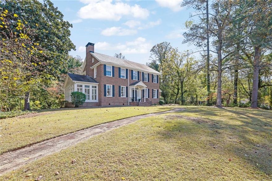 120 Jeanette Street is a rare blend of architectural pedigree, craftsmanship, and tranquility — where classic Georgian design meets timeless Southern living.

Designed in 1929 by Ivey & Crook, one of Atlanta’s most respected architectural firms, this distinguished residence exemplifies the Georgian Revival style — perfect symmetry, balanced proportions, and understated elegance.

Constructed of rich red brick with contrasting black shutters, the façade presents a stately yet welcoming presence. A columned portico with fluted supports and a triangular pediment frames the front door, adorned with original sidelights and a delicate fanlight transom — glowing in afternoon sun and setting the tone for the craftsmanship within.

A brick walkway winds through the front lawn, softening the symmetry and leading to the entrance. Mature trees, sweeping lawns, and thoughtful siting on three acres create a sense of quiet grandeur — spacious yet intimate. At the rear, a charming pool and pool/guest house with 1 bedroom and 1.5 bath offer a relaxed counterpoint to the home’s formality, ideal for entertaining or private retreat.

Inside, graceful proportions, sunlight, and original details define the interiors. The central foyer showcases hardwood floors, intricate moldings, and a sweeping staircase that rises with understated elegance. Flanking rooms — a bright formal living room centered on a carved mantel and a balanced dining room overlooking the lawn — reflect Ivey & Crook’s mastery of flow and proportion.

To one side, the formal living room centers on a traditional fireplace with a carved mantel and flanking windows that fill the space
with natural light. The dining room on the opposite side mirrors this sense of proportion — bright, balanced, and open, with original
millwork and double windows that look out to the beautiful lawn. Together, these rooms create an ideal setting for both entertaining
and quiet evenings.

The kitchen, filled with morning light, retains its vintage footprint and offers potential for sensitive modernization. Adjoining rooms provide inviting informal spaces, including a breakfast room with original glass-front cabinetry.

Upstairs, four bedrooms continue the home’s timeless symmetry, with high ceilings, ample windows, and 1920s craftsmanship. Light shifts beautifully throughout the day, and two and a half baths serve the upper and main levels.

The basement, with original plumbing and electrical connections, includes a long-unused bath — a glimpse into the home’s early
design foresight. It offers flexible space for storage, a workshop, or future renovation. The three-acre property unfolds gently
around the home, with manicured lawns, mature magnolias, and a natural sense of privacy. The pool and pool house, added later,
harmonize beautifully with the landscape, giving the estate a quiet, resort-like quality.

Lovingly cared for by only two families since 1929, this home stands as a living testament to Ivey & Crook’s enduring Southern grace, proportion, and light.