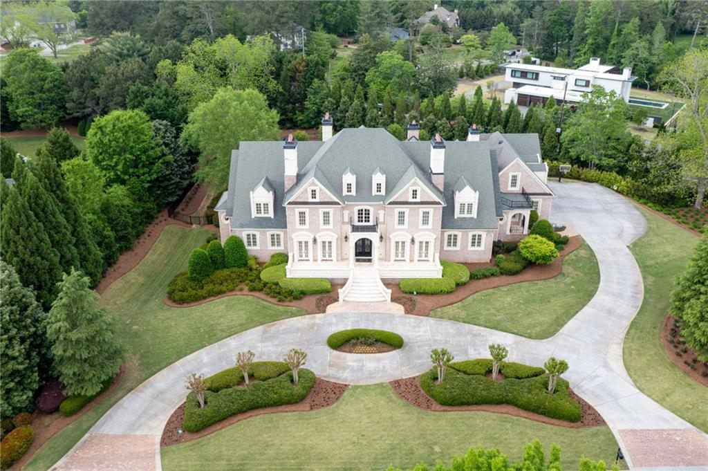 Gorgeous Custom built estate home on 2.3 acres in Glenayre, a gated guarded neighborhood in Roswell. This custom designed luxury estate will not disappoint with 4 sides brick, 7 HVAC, 8 Fireplaces, 3 theaters, 2 laundry rooms and in-law suite with kitchenette. The approach is stunning with 12” glass and wrought iron entry doors, and upon entry you will be greeted by stunning architectural details and a sweeping circular staircase, marble floors and an open floorplan that basks in natural light. Additional features include a gourmet kitchen with beautiful furniture grade cabinetry, glass door fronts and designer uplighting. Exotic granite countertops, commercial grade stainless appliances, large breakfast bar, and breakfast area and open to an elegant keeping room with cathedral ceiling, built in bookcases, fireplace and access to the patio. There is a catering/butler pantry hidden behind the main gourmet kitchen and offers built-in upper and lower cabinets, granite countertops, sink, perfect for the entertainer! There is a grand dining room to seat 16 comfortably and boast double French doors and heavy detailed trim. The mud room features building lockers, coat racks and cubbies and is convenient to the laundry room. The highly detailed study is a showstopper with hand milled stained wainscoting, coffered ceiling, accented by a limestone fireplace. Elegant owners' suite boasts coffered ceiling, designer lighting, fireplace, a morning bar with refrigerator and granite countertops, spa-like bath includes a walk-in travertine shower, soaking tub, his and her vanities with dedicated make-up seating, and a grand dressing room with a center island. Upper level offers 4 bedrooms all with en-suite baths and large walk-in closets, 2nd laundry and theater room. Terrace level does not disappoint with a large bar with beautiful cabinetry and granite countertops overlooking the billiard room. A bedroom suite with full bath and kitchenette. Additionally, there is the workout room, 2 full theater rooms, game room, learning/study room, and sports room and potential for a 5th car garage. The property is a private outdoor paradise and features a waterfall wall from the spa into the saltwater pool, and there are fountains in the tanning shelf and an expansive travertine pool deck. The screened lanai with fireplace and large seating area overlooks the manicured oasis. Minutes away from the best public and private schools, close to shopping and parks and easy access to downtown.