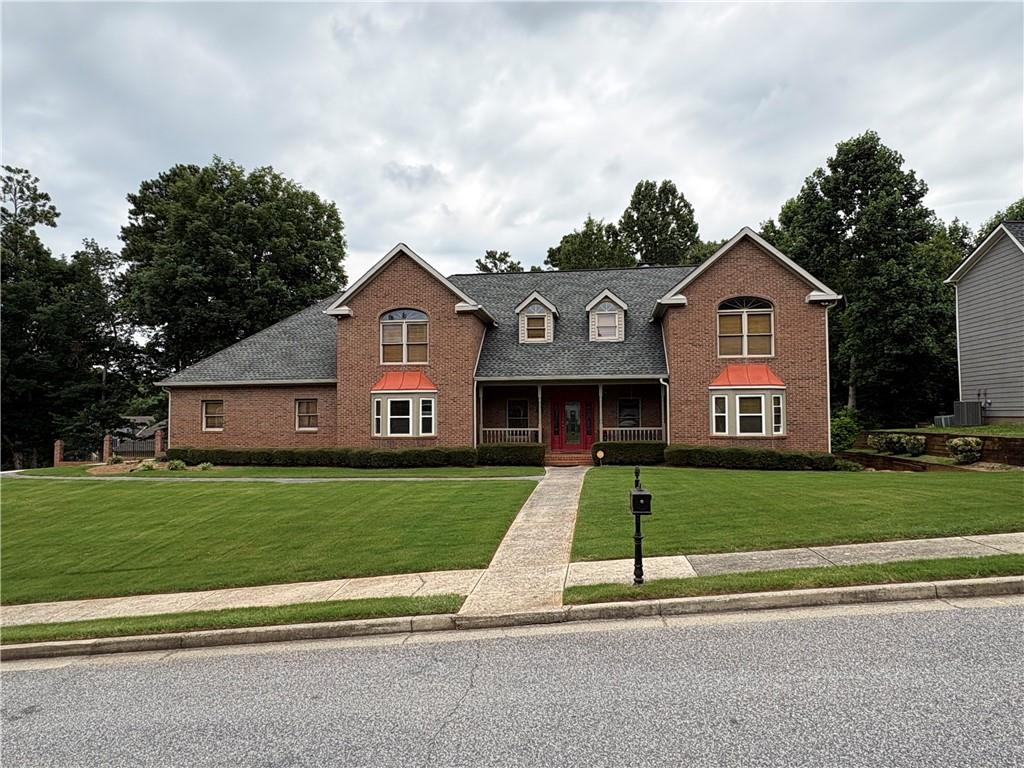 Brick two-story residence featuring a covered front porch and a distinctive red entry door