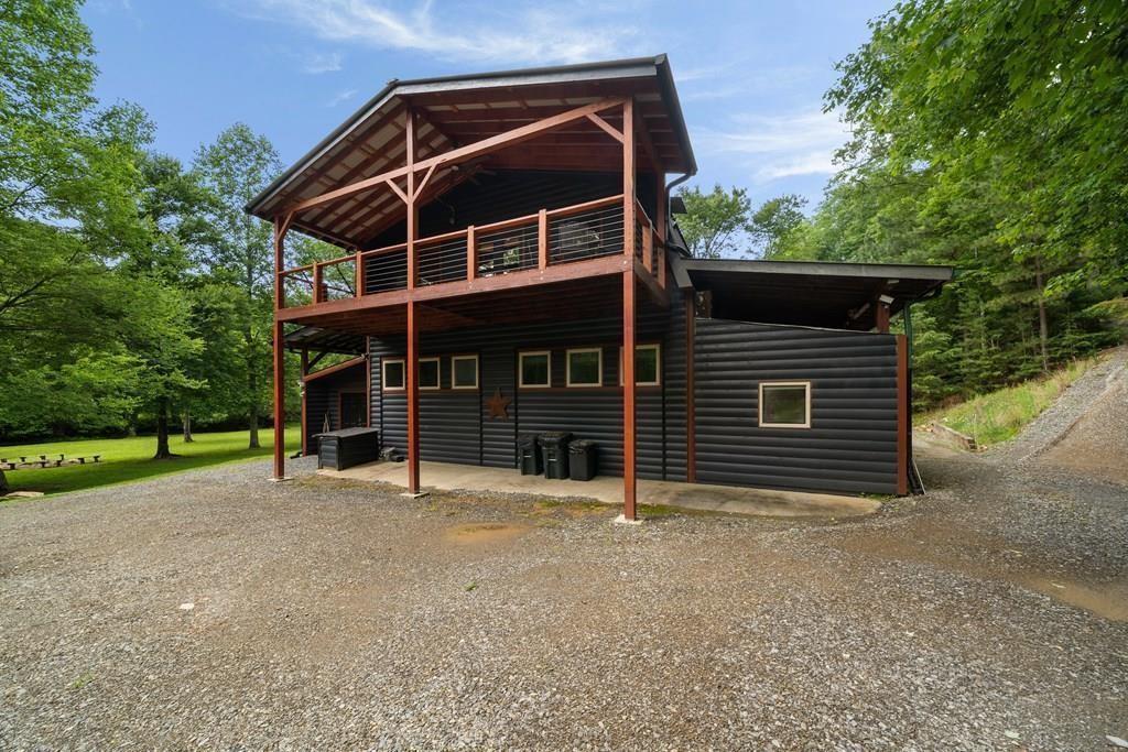 Experience the ultimate in mountain luxury with this stunning mostly TURN-KEY and FURNISHED 3BR/2BA + 2 half-bath custom rustic cabin nestled along approx. 203 feet of bold Weaver Creek frontage in the heart of North Georgia. Located just minutes from Blue Ridge inside the city limits and the sought-after Aska Adventure Area, this no HOA, no restrictions property offers exceptional potential as a high-performing short-term rental with a rental projection from Grand Welcome from $44,700 to $58,400, and could be more with amenities! Or a perfect second home, or full-time private retreat. The main level features a spacious primary suite with spa-like bath, complete with an oversized custom dual-head tile shower, his-and-hers vanities, and premium LVP flooring. The chef's kitchen impresses with soaring ceilings, stainless steel appliances, a striking copper farmhouse sink, wall oven, built-in microwave, 6-burner gas cooktop, custom wood cabinetry, pantry, and an expansive island perfect for entertaining. An open dining area flows seamlessly into the grand living room, where you'll find a wood-burning stove, gas fireplace, and exquisite 18th-century reclaimed tin ceilings-creating an ambiance that is both warm and elegant. The main level also includes a half bath and laundry room for added convenience. Upstairs, enjoy a spacious loft-style second living area, two additional bedrooms, a full bath, and an additional half bath, along with a game room featuring a pool table and two additional gas fireplaces. Step out onto the private second-story porch to take in the peaceful sights and sounds of the creek below. The exterior is equally impressive, offering a screened-in porch, hot tub, fire pit area, flat, usable backyard, and an outbuilding for extra storage. Five total fireplaces (four interior, one exterior) ensure year-round cozy comfort. Other highlights include big sliding French doors, an electric vehicle charger, and total privacy-surrounded by natural beauty, yet only minutes from premier local attractions like the Blue Ridge Scenic Railway, Mercier Orchards, top hiking and biking trails in the Cohutta Wilderness and Pinhoti Trail, Toccoa River adventures, and some of North Georgia's most popular wineries and breweries. Don't miss this rare opportunity to own a luxurious, fully furnished mountain escape at 110 Old Indian Trail-where rustic elegance meets modern convenience in one of Blue Ridge's most tranquil creekfront settings.