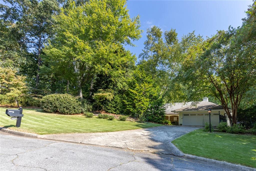 Discover an extraordinary one-and-a-half story custom residence, perfectly tucked away on a picturesque, professionally landscaped estate-sized cul-de-sac lot of over an acre. A private sanctuary, this property offers terraced walkways, lush gardens, and a serene backyard retreat with a heated Pebble Tec pool, waterfall spa, custom stonework, and seasonal views of Lake Northridge. Every detail inside and out reflects timeless craftsmanship and thoughtful design. The home welcomes with a charming front porch and tranquil fish pond, opening into a dramatic two-story stone foyer. Vaulted, beamed tongue-and-groove ceilings, expansive casement windows, and gleaming hardwood floors create a warm and airy flow throughout. The open-concept living and dining rooms boast soaring 20’ ceilings, while the beautifully renovated kitchen is a chef’s dream—custom cabinetry with Rev-a-Chef accessories, quartzite countertops, tile backsplash, center island with seating, stainless steel appliances including gas cooktop and vent hood, microwave drawer, and a convenient Butler’s Pantry. A separate breakfast room offers the perfect everyday gathering spot, while the spacious family room—with its Palladian window, stacked-stone fireplace, and wet bar—opens directly to the terrace, blending indoor and outdoor living for effortless entertaining. The terrace itself overlooks the sparkling heated pool and fenced backyard, designed for both relaxation and family enjoyment. Features include lighted walkways and stairs, a pool cabana conveniently located off the terrace, pool storage, custom stone terraces, Trex decking, an automatic pool cover, and Jandy Aqua Link RS system—all creating a resort-like setting for gatherings large or small. The main-level primary suite offers a peaceful retreat with his-and-hers closets and a spa-like bath. Two additional bedrooms (one with custom built-ins) share a hall bath, while a large laundry room enhances main-level convenience. Upstairs, a light-filled loft with skylights overlooks the living room, alongside a spacious bedroom with full bath and generous walk-in attic storage. The terrace level features soaring ceilings and a fully equipped in-law suite/apartment with private entrance, including living and dining rooms, a full kitchen, bedroom, and full bath with step-less shower, plus abundant storage and workshop space. This exceptional property is ideally located near top-rated public and private schools, shopping, and dining, with easy access to Sandy Springs City Center, Dunwoody Village, downtown Roswell and Alpharetta, and GA 400. Residents enjoy a private neighborhood entrance to the scenic Island Ford Chattahoochee River Park, as well as proximity to Dunwoody Golf & Country Club. A rare offering, this home combines the beauty of nature, architectural distinction, and versatile family living into one unforgettable estate.