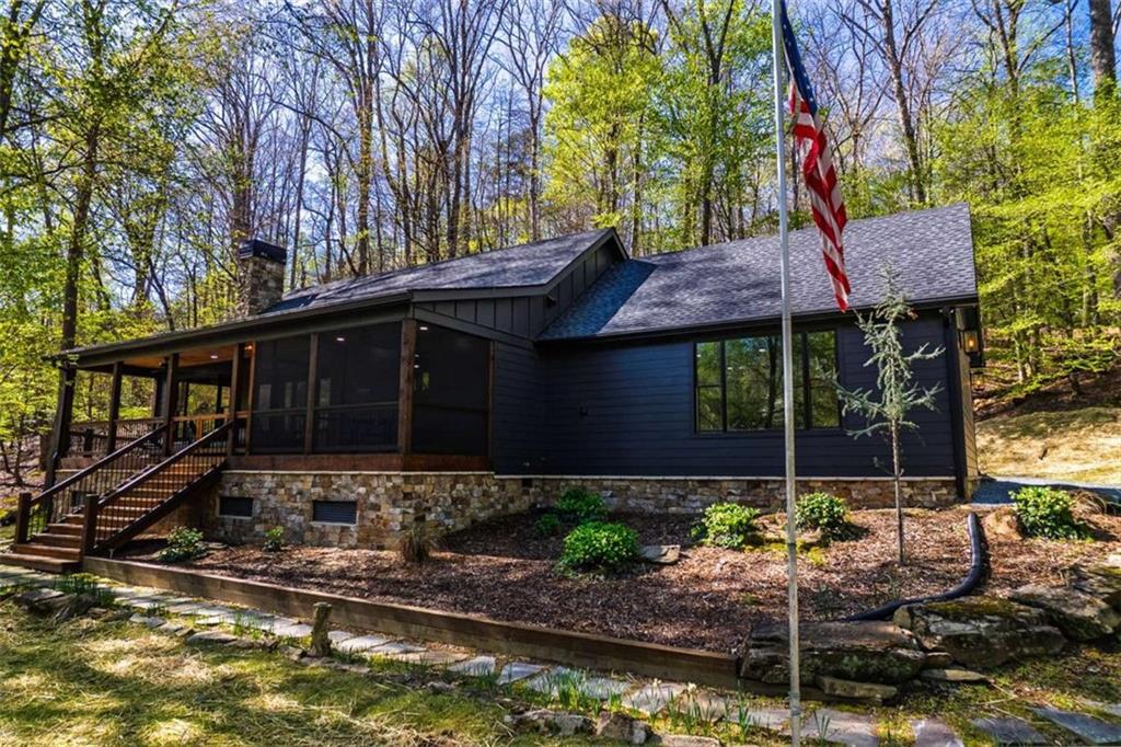 PRICE JUST REDUCED BY $105,000-MOTIVATED SELLER. This extraordinary riverfront cabin has been completely rebuilt from the studs up-everything is brand new. The seller opened up the main living space by removing the center wall, creating a spacious, airy feel anchored by a stunning, oversized stone wood-burning fireplace. A brand-new bedroom and bathroom have been added, and all ceilings have been beautifully finished with wood for a warm, rustic touch. The expansive kitchen is a dream, featuring stainless steel appliances, quartz countertops, and an abundance of custom cabinetry. The primary suite includes a bright, open sitting area-perfect for enjoying a quiet morning coffee. All three bathrooms, including the newly added one, have been fully renovated with thoughtful, high-end finishes. Nestled on 1.93 acres, the property boasts over 450 feet of pristine river frontage. The front porch is partially screened in, offering a serene spot to unwind and listen to the soothing sounds of the river. Outdoor amenities include a riverside dock, a large firepit, a hot tub, a rear stone patio, and a separate workshop/storage building. Located at the end of a private road, this one-of-a-kind gated retreat offers both privacy and peace of mind. A truly special property-don't miss your chance to experience it.