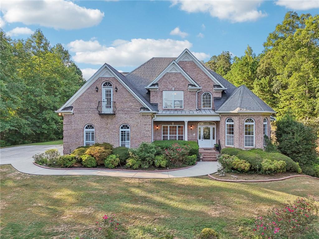 Welcome home to this stunning, custom built 4-side brick estate home in Villa Rica. This elegant home features 5 bedrooms, 4 full bathrooms, and 2 half bathrooms (1 Jack and Jill bathroom) and approx. 4,850 square feet of luxurious living space, situated on 5 private and serene acres. Main level features a dramatic 2 story hardwood foyer and soaring ceiling flanked by a formal dining area with arched doorway, decorative columns, art niches, intricate inlaid tile and hardwood floor and sophisticated trim work throughout. Just beyond the foyer lies the grand gathering room with coffered ceiling & tower of windows that drenches it in natural light. From grand room there is an open view to the breakfast area and kitchen. The gourmet kitchen offers cherry cabinets, stone countertops, stainless steel appliances, large pantry, and breakfast bar. Just beyond the kitchen is the vaulted Keeping room with decorative wood burning fireplace and bar area. French doors open to the newly renovated deck overlooking the private, level 5 acre back yard. The main level also features the spacious primary suite boasts a sitting area and luxurious ensuite with whirlpool spa tub, large separate tile shower, heated ceramic tile floors, dual walk-in closets and double vanities. The upper level features a loft/office area along with 2 secondary bedrooms, one which is a guest suite that includes a patio/balcony and full bath. Last but not least, the expansive terrace level presents like a 2nd home with a full kitchen, 2 bedrooms, 2 full bathrooms, surround sound media/game/billiards room that would be perfect for in-law or au pair suite. Home is also equipped with built in 7 camera security system and is conveniently located near schools, shopping, dining and. I-20 for quick commuting.