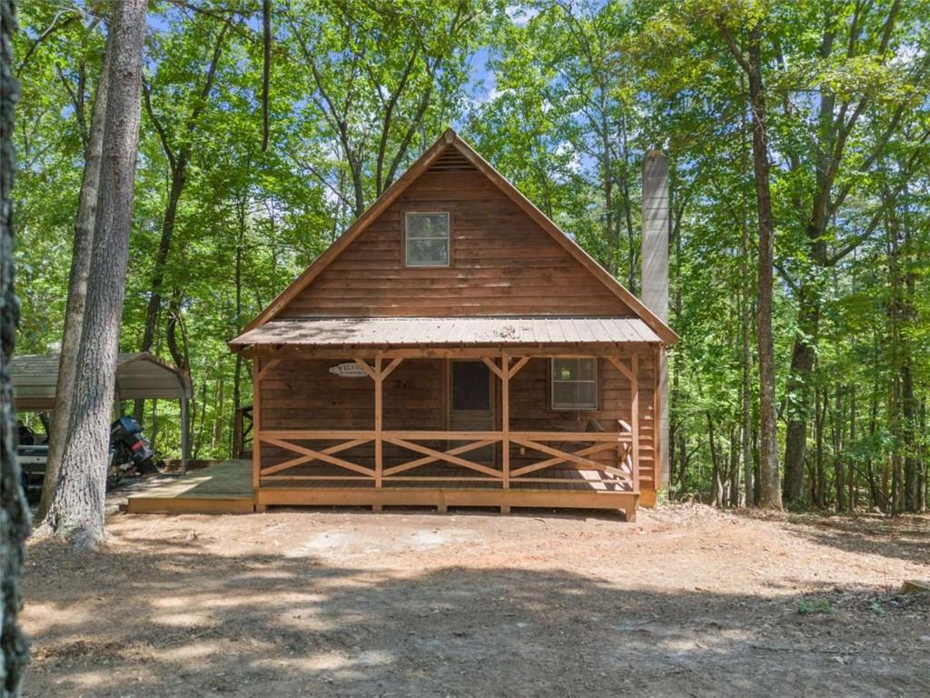 Nestled on more than four acres, this mountain retreat strikes the perfect balance between peaceful seclusion and easy access to town-just minutes from the University of North Georgia and downtown Dahlonega. The cabin's light-filled interior showcases vaulted ceilings and hardwood floors on the main level, creating a warm and inviting atmosphere. The primary suite is conveniently located on the main floor, with two additional bedrooms on the lower level to comfortably accommodate family and guests. A versatile bonus room upstairs offers even more living options. Outdoor living shines with two screened porches designed for year-round enjoyment. The main-level porch features a wood-burning fireplace and cozy swing, while the lower-level porch includes a hot tub-ideal for soaking under the stars on cool evenings. Surrounded by seasonal mountain views, this property provides a rare sense of privacy yet remains close to Lumpkin County's best amenities, including six wineries within five miles. With a detached carport, expansive gravel drive, and plenty of parking, hosting guests is a breeze. Whether you're searching for a full-time residence, a weekend getaway, or an investment opportunity, this unique cabin delivers mountain living at its finest.
