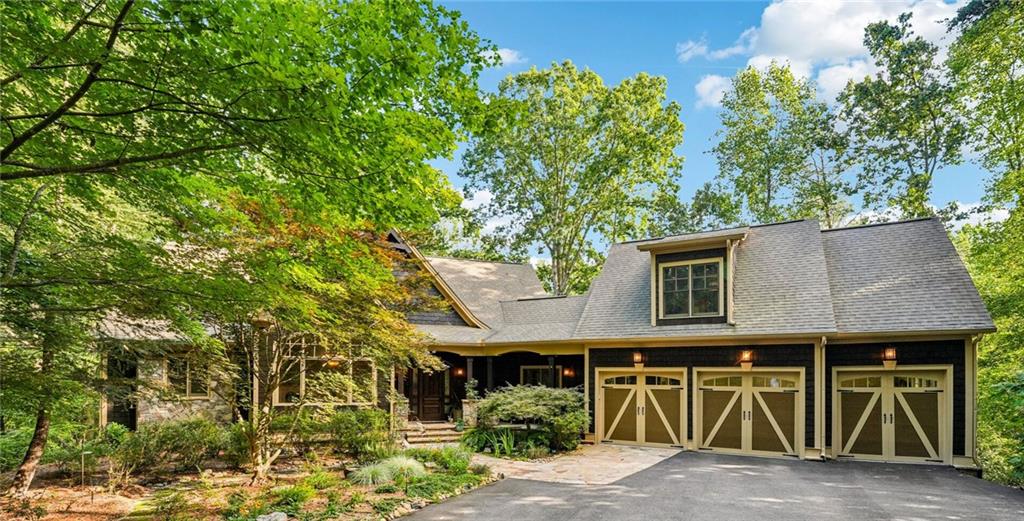 Welcome to Your Private Estate in Big Canoe’s Coveted Wildcat Neighborhood. Nestled at the end of a quiet cul-de-sac, this estate-like property offers a rare blend of privacy, elegance and convenience. A long, tree-lined driveway leads you to the three-car garage, lush landscaping, and serene water features, setting the stage for the exceptional home that awaits. Inside, soaring ceilings and rich hardwood floors create an immediate sense of warmth and grandeur. Just off the foyer, an elegant formal dining room with custom millwork, a painted mural and wall of windows overlook the forest providing the perfect setting for entertaining, music, or an executive study. The chef’s kitchen is a true centerpiece of the home, with extensive custom cabinetry, granite countertops and a large center island with seating. Tucked within the kitchen cabinetry is a hidden, walk-in pantry with built-in, wood shelving. The kitchen boasts high-end appliances: Dacor double ovens and 6-burner gas cooktop and a Sub-Zero refrigerator. Moving from the kitchen into the great room, you are greeted with vaulted, wood-beamed ceilings, a dramatic floor-to-ceiling stone fireplace, custom built-ins and expansive windows that flood the room with natural light and mountain elegance. The main level primary suite is an expansive, private retreat, featuring a spa-inspired bath with marble countertops, slate flooring and shower surround, dual vanities, custom cabinetry and a spacious, walk-in, custom closet. The main level is complete with a screened, EZ Breeze porch with a gas fireplace, a powder room and laundry room. Upstairs, an oversized, bonus suite sits atop the three-car garage and includes a full bath and closet, ideal for a private guest space, hobby room or office. The terrace level, with 10 foot ceilings and walls of windows, is designed for entertaining. The space features a full wet bar appointed with leathered granite, river rock backsplash, refrigerator and custom dishwasher drawer. This level also includes a large, additional living space with a stone fireplace that flows into a spacious, recreation area. Guests and family will enjoy the three additional bedrooms - one with custom built-ins, perfect for a home office - and two full bathrooms. Finally, the outdoor space is truly one-of-a-kind with extensive living spaces that include a covered front porch, large terrace level flagstone patio and secluded seating surrounding the tranquil fish pond. Peaceful, nature trails meander through the perennial gardens and into the fully, fenced backyard, where you have direct access to the popular Red Loop Trail in Wildcat. From its premier setting and architectural details to its luxurious finishes and thoughtful amenities, every detail of this property reflects quality and care. This is a rare opportunity to own one of Big Canoe’s finest private retreats.