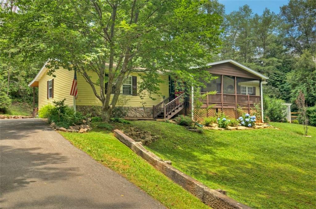 Welcome to this adorable, affordable, and spacious home that combines charm, comfort, and practicality in one attractive package. Meticulously maintained, this residence features numerous builder upgrades that enhance its appeal and functionality. As you step inside, you'll be greeted by a warm and inviting living space. The cozy stone fireplace adds character and provides a welcoming focal point, while the sleek laminate wood flooring stretches throughout the home, offering both style and durability. The dining area is generously sized, comfortably accommodating 6-8 guests. The well-designed kitchen offers ample cabinet and counter space, allowing for efficient meal prep and storage. Large walk-in closets in all the bedrooms provide abundant storage options, helping keep your living spaces organized and clutter-free. The owner's suite features a luxurious master bathroom with a relaxing corner soaking tub, perfect for unwinding after a long day. The separate shower and dual-sink vanity add convenience and appeal, making daily routines easier for everyone. Step outside to the screened-in porch, an enchanting spot to savor your morning coffee or unwind in the evening while enjoying the tranquil surroundings. The gently sloping lot offers plenty of room for children to play, run around, or gather around the fire pit for roasting marshmallows and enjoying evening conversations. The back covered deck is wheelchair accessible, demonstrating thoughtful design and inclusivity while offering a shed/workshop as well. There's a fenced-in area that's perfect for pets, giving them a safe space to roam freely. For ultimate relaxation, a hot tub awaits you, inviting you to de-stress and enjoy outdoor leisure. Parking is conveniently accessible with ample space.There's also a 10x16 storage building! Most importantly, this home sits on a permanent foundation, qualifying it for traditional financing options, making it an excellent choice for buyers looking for affordability!