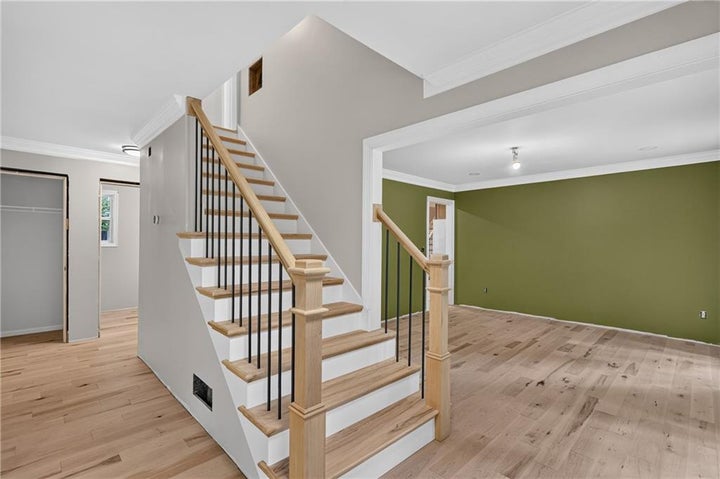 Hardwood flooring throughout the main level complements the staircase featuring natural wood handrails and black metal…