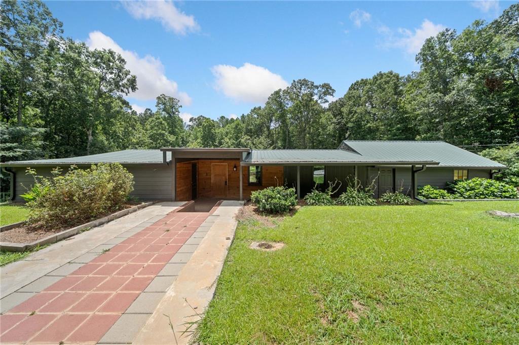 Rustic charm meets modern comfort on this beautifully renovated home tucked away on 1.21 private, wooded acres. From the vaulted ceilings with exposed beams to the custom wood paneling and striking bamboo floors with detailed inlays, every corner of this home offers something unique. The open-concept living space features an electric fireplace and flows into a stylish kitchen with shaker cabinets, butcher block countertops, stainless steel appliances, a farmhouse sink, and thoughtful updates throughout. The bathroom stands out with a tiled tub/shower accented by mosaic details and a custom vanity. Step outside to a freshly painted exterior, a spacious back deck, covered parking with both a carport and detached garage, plus an outbuilding for extra storage or workshop space. With a brand-new HVAC system and a peaceful setting just minutes from town, this one is truly move-in ready and full of character!