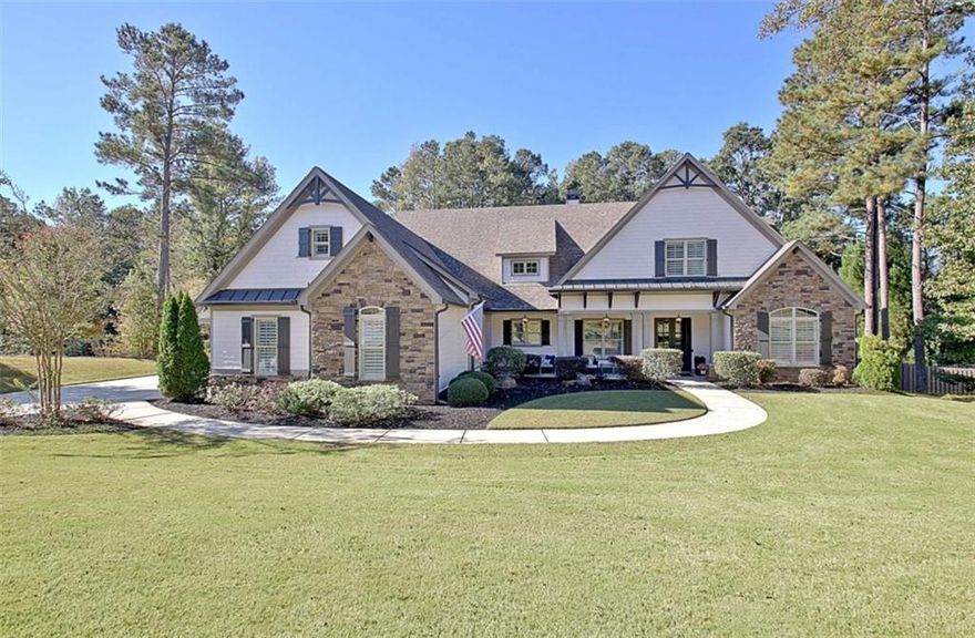 Effortless style and timeless craftsmanship come together in this beautifully designed Northwynn home! Step through the double front doors into a warm, inviting foyer where rich hardwood floors and a wood-planked ceiling set the tone for relaxed elegance. The open layout flows seamlessly into a vaulted great room accented by exposed beams, custom built-ins, and a stacked-stone fireplace. To the left, a formal dining room offers wainscoting, a tray ceiling, and soft natural light filtered through custom wood shutters. The kitchen is a showpiece with timeless white cabinetry, granite countertops, tile backsplash, 36" 5 burner gas cooktop, wall oven, wine cooler, and a generous island with seating. A walk-in pantry/wet bar/mudroom with custom pull-out shelves keeps everything organized and accessible. The serene primary suite on the main level features a tray ceiling with tongue-and-groove detail, a private door to the porch, two closets, and the spa-inspired bath includes dual vanities with granite counters, a soaking tub, and a large walk-in shower with dual heads and a built-in bench, all finished with elegant tilework and bronze fixtures. Upstairs, a spacious bonus room offers endless flexibility: ideal for a media room, additional living area, guest room, or home office, and a large, walk-in attic with spray foam insulation for exceptional storage in a comfortable environment.  The covered patio features a BBQ center with stone surround and natural gas, ceiling fan, and a wall mounted TV for easy entertaining. The vaulted screened gameday porch extends the living area, complete with a floor-to-ceiling stone fireplace, ceiling fan, bistro lighting, and speakers that can connect to a central entertainment system. The oversized three-car dream garage features an epoxy floor and room for vehicles, tools, or a home gym. The beautifully landscaped, private, fenced yard, and picture-perfect curb appeal complete this incredible property. Every space in this four bedroom, four bathroom (plus a bonus!) home has been thoughtfully designed for livability, luxury, and low-maintenance enjoyment, with a location convenient to PTC, Newnan, Senoia, shopping, and dining!
