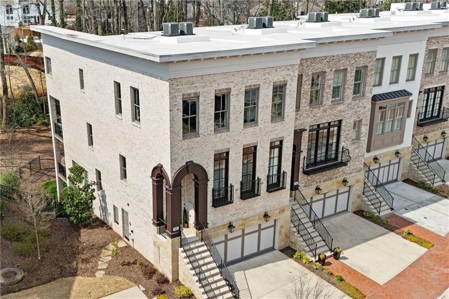 Exquisite End-Unit Townhome in the Heart of Downtown Alpharetta’s Sought-After Windsong Community! Step into luxury where impeccable design meets unparalleled functionality. The entryway opens to a chic lounge (or optional dining room) featuring a striking 3D electric fireplace—perfect for entertaining. A wet bar awaits beyond, complete with an ice maker, beverage cooler, sink, and custom cabinetry for effortless hosting. Refined and recently refinished hardwood floors flow throughout, complemented by intricate inlays in the foyer and landings. The powder room is a showstopper with a floor-to-ceiling mosaic marble accent wall and a bespoke white oak vanity crowned with a hand-carved dolomite marble vessel sink. At the heart of the home, the gourmet kitchen stuns with high-end appliances, a brand-new waterfall-edge island, marble countertops, and Keystone custom cabinetry. The oversized island in the chef’s kitchen compliments the cozy and chic fireside family room, which is elevated by a striking walnut mosaic fireplace flanked by floating walnut shelves. Adjacent, a sunroom with a Spanish tile accent wall leads to a private deck with serene backyard views. The upper-level owner’s suite is an oasis with substantial custom walk-in his-and-her closets. The spa-inspired bath covered in Statuario Marble slabs features top-of-the-line cabinets, double vanities, and a double-headed walk-in shower. Your private coffee bar with a Miele Coffee Machine and a beverage cooler awaits you every morning and evening. Outside the Owner’s suite is the laundry room, which includes a sink and hanging rack, a secondary bathroom, and two spacious secondary rooms with custom closets. The finished basement level is a versatile retreat currently designed as two guest rooms with a second laundry room, and a convenient full bath. The additional guest suite can be rearranged as a media or sitting room. With built-in plumbing, future owners can add a wet bar for extra entertaining space. On the second level, a three-car garage with sleek “granite” epoxy floors offers ample storage. This floor also features a mother’s desk, a mud room, elevator access, an additional bedroom with an ensuite bathroom, and an adjoining sitting room with yet another covered porch. Additional features include custom cabinetry throughout, custom wall treatments, plantation shutters, upscale modern light fixtures, whole house water filtration system, and an ample fenced backyard. All this luxurious living space right in Downtown Alpharetta