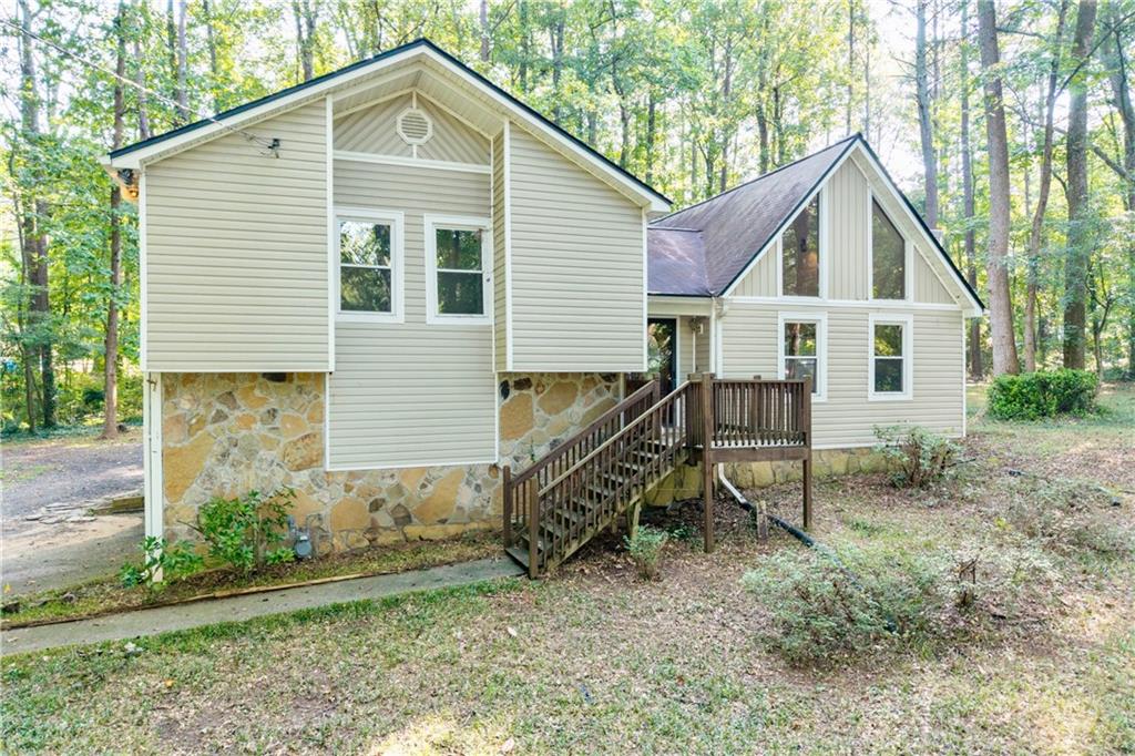 Rare opportunity to possess a 3 bedroom, 2 bathroom home sitting on 1.64 ACRES!!! This home is perfectly secluded, private, and serene, tucked away at the end of a culdesac in a quiet neighborhood. Be greeted by a high vaulted ceiling Living Room and a unique stone fireplace. Appreciate New Windows throughout the home that grants plush views of nature and the flat yard that surrounds the home. Step outside to a large, expansive deck, perfect for relaxing or entertaining in your own private retreat. The acreage offers endless possibilities — park your RV, build a detached garage or workshop, or even explore the option of an additional dwelling. Properties like this are hard to find — over 1.5 acres of land in a central location, just 20–25 minutes from Smyrna, Kennesaw, Hiram, and Marietta Square.