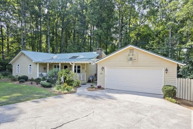 Charming Cottage-Style Home with Guest House on Nearly 2 Acres - No HOA! Rare opportunity! This beautifully maintained property offers two homes on almost 2 private acres with no HOA just minutes from Lake Lanier, GA-400, and downtown Cumming. The main home is full of cottage-style charm and in excellent condition, featuring a main-level master suite with vaulted ceilings, double vessel sinks, and an oversized dual rain shower. The open living space includes a cozy family room with skylight, hardwood floors throughout, and a kitchen with granite counters, travertine tile, and a charming cottage-inspired island. The sunlit dining room overlooks a wooded, private backyard. A finished basement offers a bedroom, living space, and extra storage. The second home is fully renovated, ideal for guests, in-laws, or rental income. It includes 2 bedrooms, 1.5 baths, granite countertops, beautiful cabinetry, wood flooring, and a spacious living area. Located in a peaceful, quiet area just 0.5 mile to GA-400 and close to parks and shopping. Move-in ready and a true must-see!