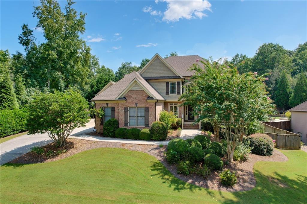 Stunning 6 Bedroom, 5 Bathroom Home on Basement with Home Theater - One of the Largest Floor Plans in the Highly Sought-After Orange Shoals Community! This home features a rare private studio apartment over the oversized 3rd Car Garage, perfect for a home office, bonus room or in-law suite. Upon entry, you are greeted by a two-story foyer with hardwood floors that flow seamlessly into the family room featuring a stone fireplace & access to the extended covered deck with wood-paneled ceiling. With views overlooking the large fenced-in backyard with a pergola, café lighting, patio stones & swings! Off the foyer, you’ll find a versatile living room or office space, while the separate dining room features chair molding and a luxury linen light. Extensive Crown and Picture Rail Molding can be found throughout the Home. The chef’s kitchen boasts custom cabinetry, luxury stainless steel appliances including double wall oven with side-swing doors & refrigerator with a beverage center plus double-door pantry. It also includes a breakfast bar with beadboard accent and an open breakfast area with access to the covered deck. The main level is complete with a generous bedroom and full tiled bathroom! Upstairs, the hardwood stairs lead into the hallway which features spacious bedrooms, including an en-suite. At the heart of it all is the Loft Room, a bright and airy space, with french doors and is perfect for gaming! The Owner's Suite offers a tray ceiling, views of the landscaped backyard and an adjoining spa-inspired bathroom with vaulted ceiling, double vanities, designer lighting, an enclosed tiled shower, and jetted tub. A must-see is the massive walk-in closet that makes this owner’s suite a true sanctuary. There's even more: a Finished Basement includes a Home Theater complete with a Large Screen, Built-In Audiovisual Equipment and Speakers. Adjacent is the vast exercise/recreation room, unfinished storage areas including stubbing for a future bath! Enjoy neighborhood amenities such as a clubhouse, swimming pool, tennis courts, playground and tree-lined streets with community benches. Located just minutes from shopping, dining, and entertainment, including the city of Canton, Roswell, Milton and Woodstock this home has it all!