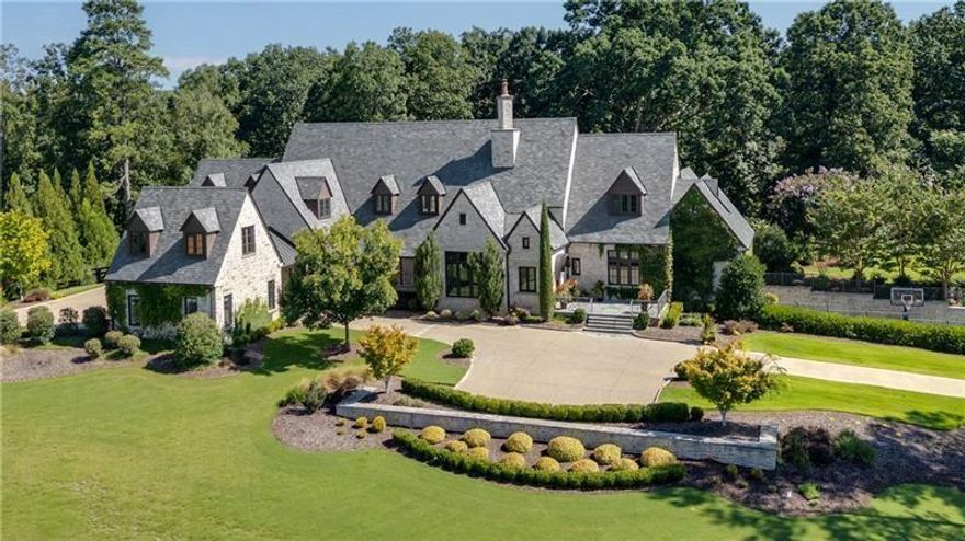 Exceptional property located on 4.58 acres within the exclusive gated community of Rivers Edge in Milton, this stunning all stone estate, adorned with a slate roof, was designed by T.S. Adams Studio. Radiating sophistication and timeless beauty, this stately residence features a commercial-grade elevator, connecting all three levels. Meticulous attention to detail is evident throughout, with the interior presenting a seamless fusion of stone, wood, and brick walls. The Venetian plaster adds a touch of timeless elegance, enhancing the overall atmosphere. The kitchen, a culinary masterpiece, showcases high-end appliances and a secondary butler's kitchen complete with a walk-in pantry. An inviting eating area opens to a panorama of windows framing the view of the pool. Continuing the seamless integration of indoor and outdoor living, the kitchen extends to the family room. French doors create an effortless transition, inviting guests to the pool area. On the main level, an office overlooking the pool and a library flank the path leading to the owner's suite which offers incredible views of the pool. The second floor adds to the opulence with 3 bedrooms and four full baths, providing ample space for family and guests. Convenience is paramount, with laundry rooms on both the main and second floors. The basement adds to the allure with a sauna, temperature-controlled wine room, safe room, family media room, billiard area, and daylight entry to a basketball court. A fenced backyard, coupled with the pool area extending to a side yard, creates an ideal space for various activities, solidifying the estate's commitment to providing a luxurious and versatile living experience. Ample parking is provided, with a porte cochere leading to a motor court and a 4-car garage. This estate is a combination of design, luxury, and functionality, offering a truly exceptional living experience in the prestigious Rivers Edge community.