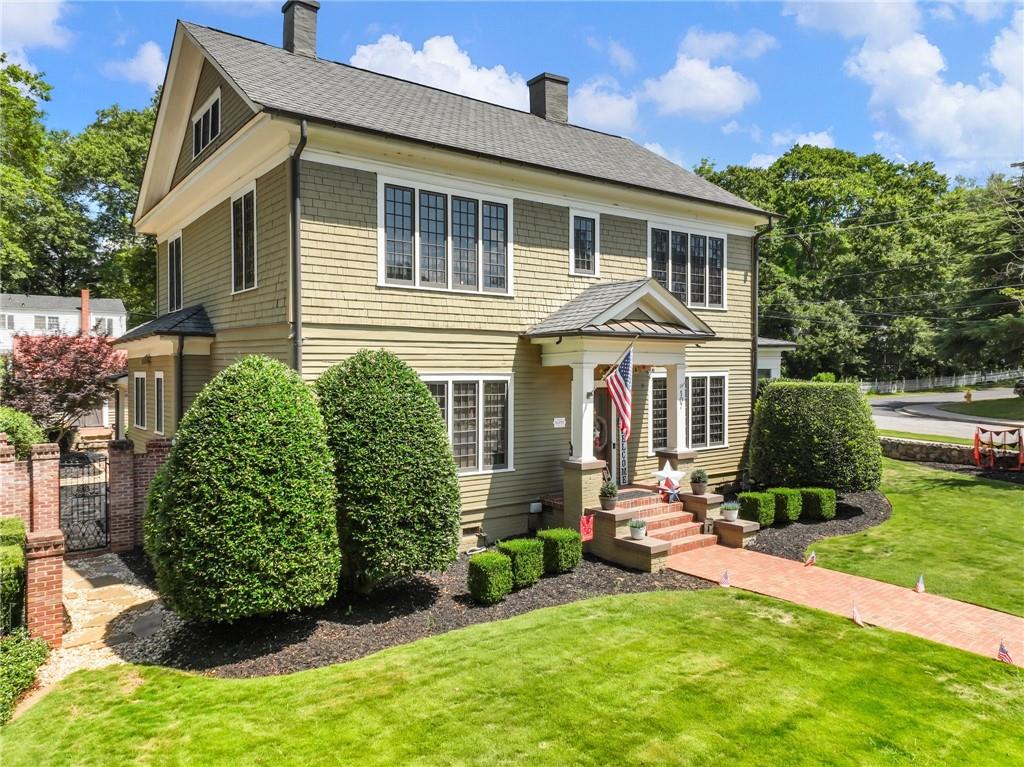 View of front of property with a chimney, a front yard, and roof with shingles