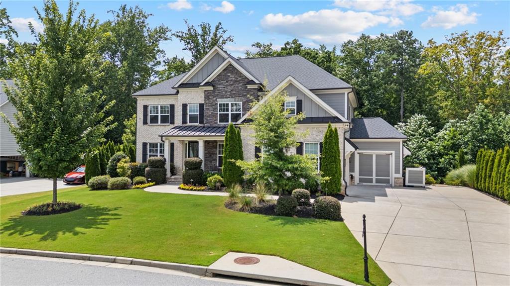 Tucked away in a sought-after community, and priced below appraised value, this expansive 6-bedroom, 4.5-bath, 3 car garage estate on a FULLY FINISHED TERRACE with a SECOND KITCHEN AND LAUNDRY redefines luxurious living with over 5,500 square feet of space. The stacked stone, brick, and board-and-batten exterior creates a stunning contrast that highlights the inviting covered front porch. Auto enthusiasts will appreciate the garage’s unique features, including 8-ft doors, pure white polyaspartic epoxy floors, slat wall organization, and a third carriage garage pre-wired for a 4-post lift. Add in a mounted commercial-grade opener and an integrated EV charger, and you’ve got the ultimate setup for storage, tinkering, or showcasing your prized vehicles. Inside, discover wide-plank engineered hardwood flooring that spans the entire home. French doors open into a formal living room or possible home office. The open layout is anchored by a true chef’s kitchen, outfitted with top-of-the-line Wolf appliances, a large island, sleek cabinetry, and generous counter space. Whether you’re hosting a dinner party or cooking a quiet meal, this kitchen is built to perform, with a connected vaulted sitting room and effortless flow onto the deck. Natural light floods the adjoining family room, highlighting the clean lines of the coffered ceiling and the cozy fireplace. A dry bar, half bath, and a full main level en-suite complete the first floor. Upstairs, you’ll find a dedicated media room, the perfect retreat for movie nights, gaming, or even a workspace. The oversized primary suite is complete with French doors leading into the vaulted bath with a walk-in tiled shower, soaking tub, and double vanity. Spacious secondary bedrooms feature walk-in closets and stylish finishes that cater to both comfort and style. Refinished hardwoods continue through the hallway, maintaining consistency and quality throughout. The finished terrace level offers a completely self-contained living space, ideal for in-laws, extended guests, or long-term multi-generational needs. Enjoy a full kitchen with a rolling island, farmhouse sink, gas cooktop, and excellent storage. There’s also a private bedroom suite, separate laundry area, and a flex space. A massive bonus room provides endless options when utilizing this space to meet your lifestyle. Custom built-ins and large windows make this lower level feel just as polished and bright as the main floors, with access to a beautiful brick paver patio. Enjoy evenings on the upgraded back deck, which comes ready for your gas grill. The wrought-iron fenced backyard provides a modern look with peace of mind. A custom flagstone pathway and steps lead from the backyard to the driveway for added convenience while hosting, making it as functional as it is attractive. Professionally landscaped around the entire property, complete with in-ground irrigation and accent lighting. Four perimeter security cameras with DVR backup provide 24/7 monitoring, while LED lighting throughout boosts energy efficiency without sacrificing style or charm.
From its high-end finishes to its versatile layout, this residence delivers the ultimate package without compromise—whether you’re accommodating guests, working from home, or relaxing in style.