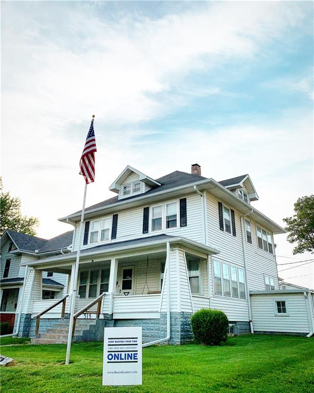 Traditional style home featuring covered porch, a front yard, and a chimney