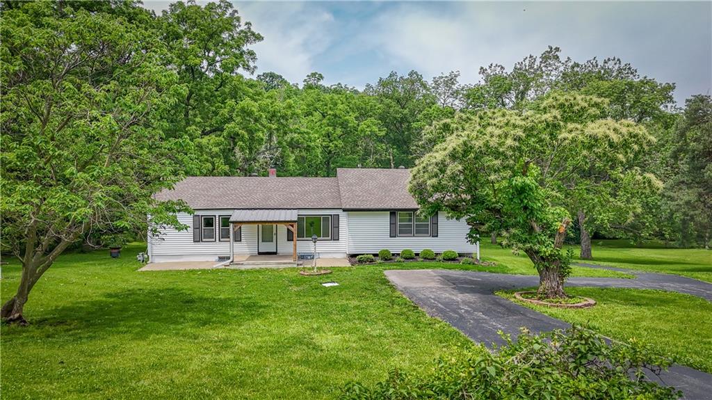Single story home featuring a shingled roof, a front lawn, and a patio