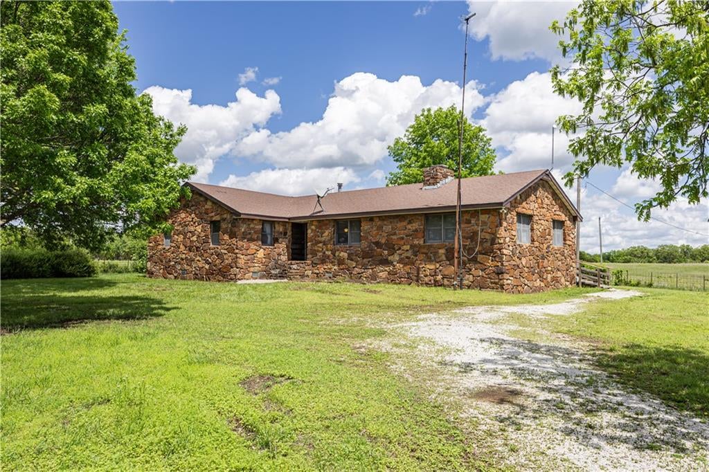 Ranch-style house featuring fence, stone siding, and a front yard