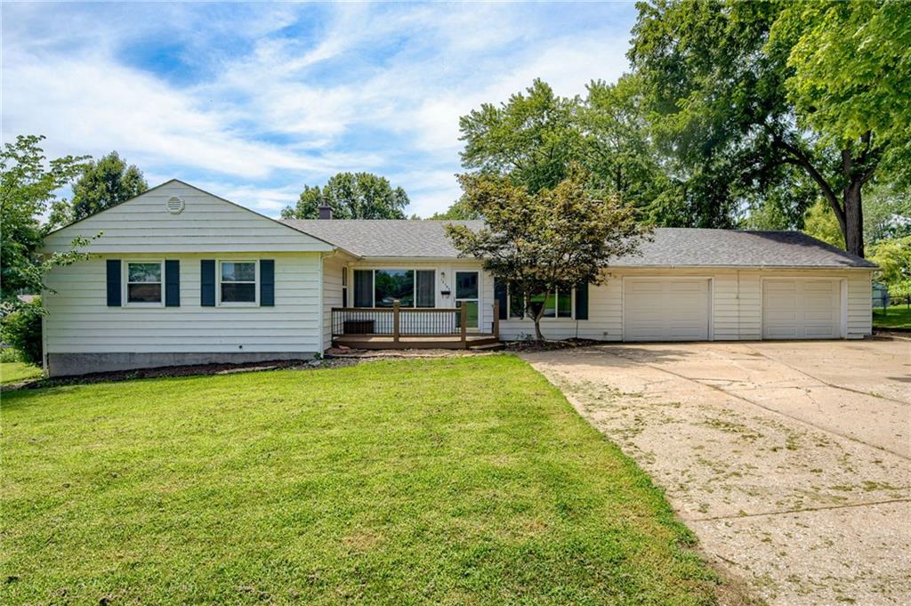 Ranch-style home with concrete driveway, an attached garage, a front lawn, and a shingled roof