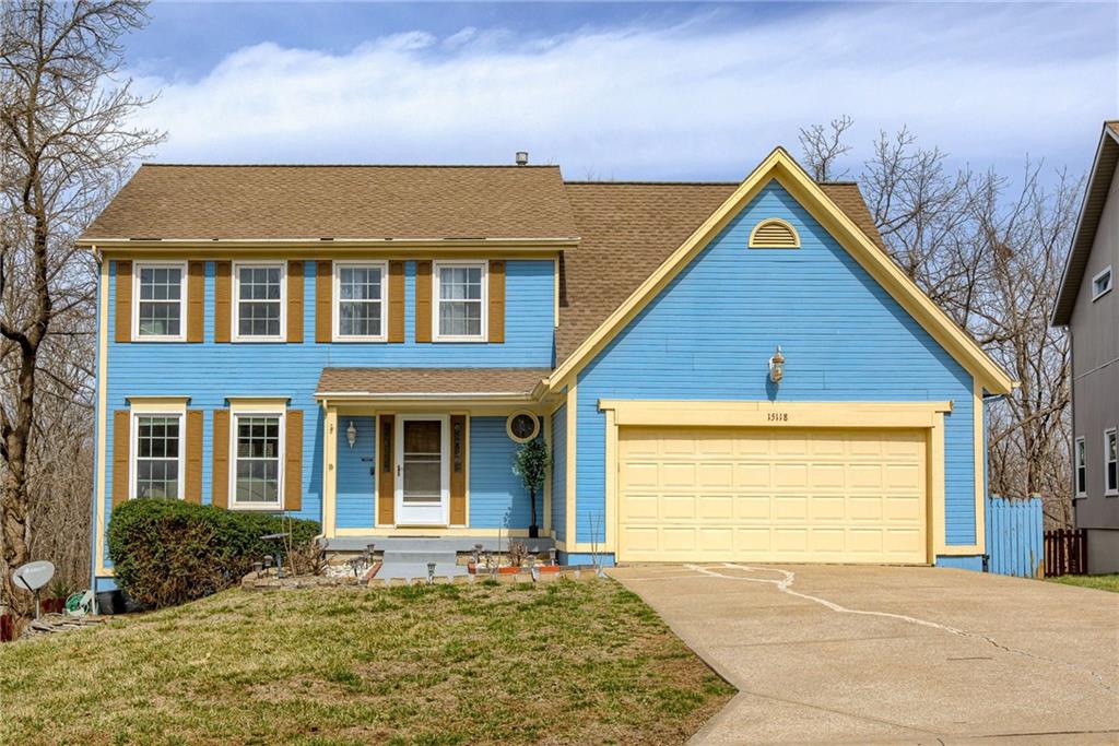 Colonial inspired home with fence, roof with shingles, concrete driveway, a front yard, and an attached garage